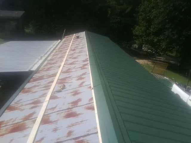 Old rusted panels beside newly installed green metal roofing — Wind Damage Roof Repair by Roofing Brothers in Mazomanie