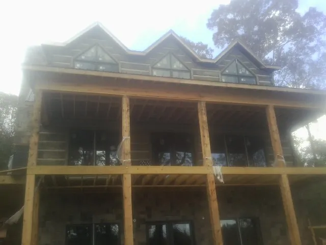 Dormers and porch framing on a large log home under construction — Roof Coating work by our crew in Mazomanie