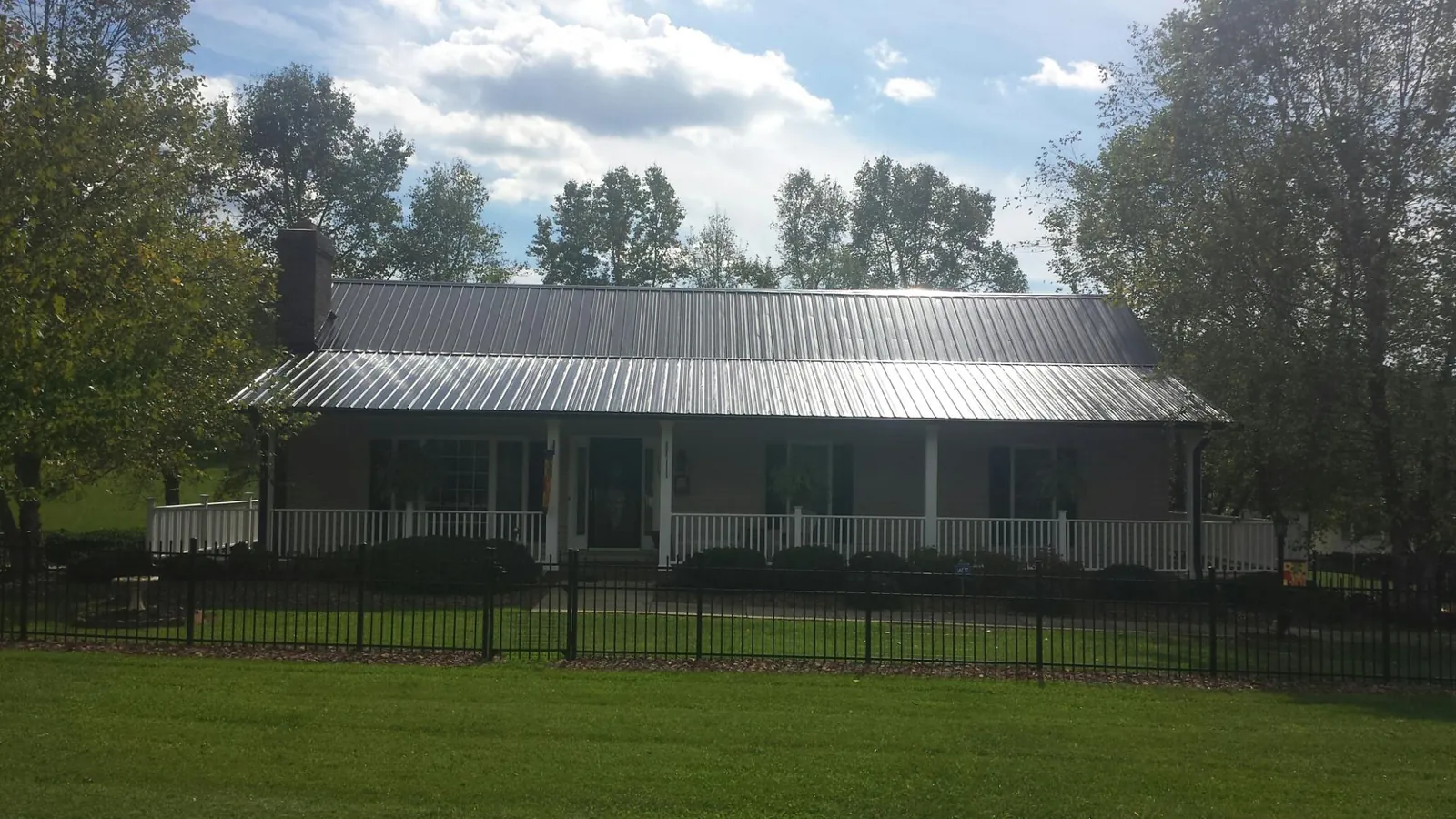 Gray metal roof on a brick ranch with a full width front porch — Gutter Guard Installation work by our crew in Mazomanie