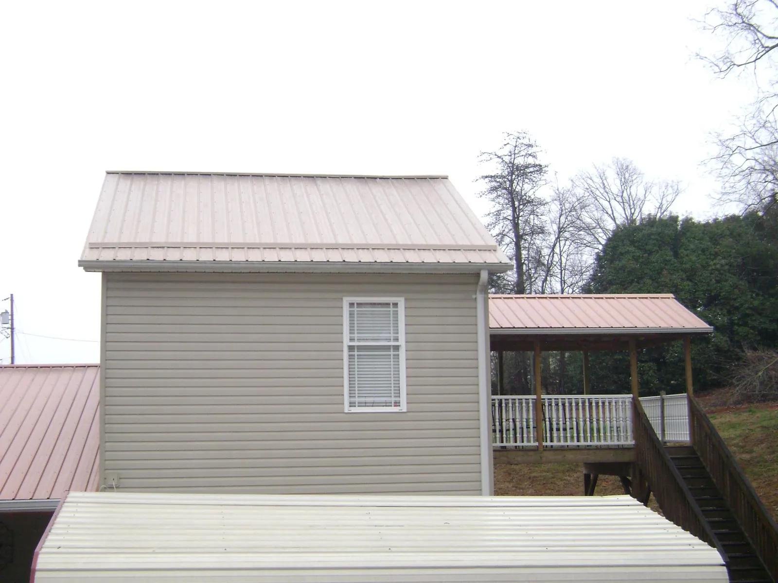 Tan metal roofs on a two story addition and attached porch, from a Roof Replacement job in Mazomanie