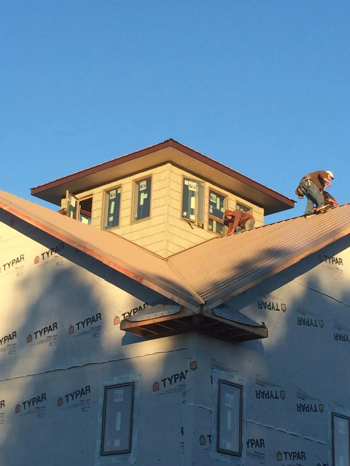 Roofers working around a rooftop cupola on a new metal roof at sunset — Roof Waterproofing in Mazomanie by Roofing Brothers